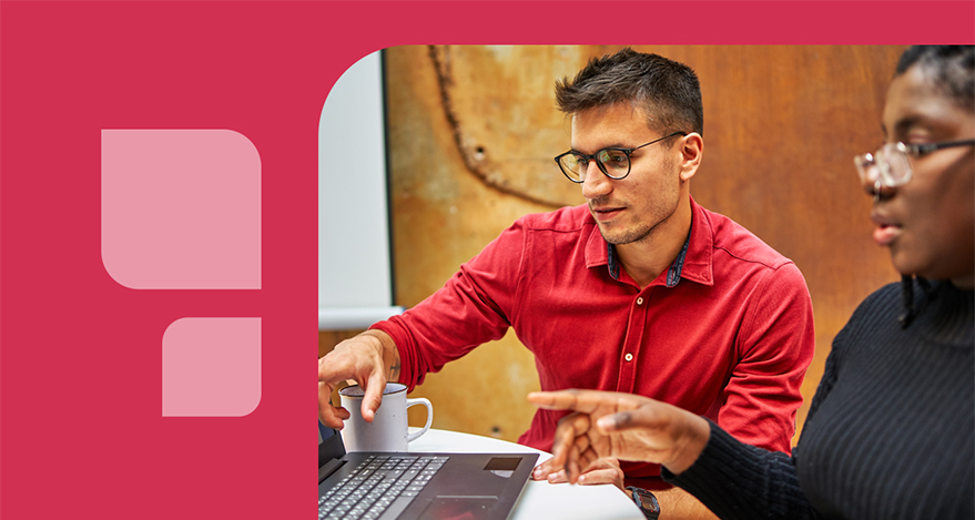 Two people look at and point to a computer