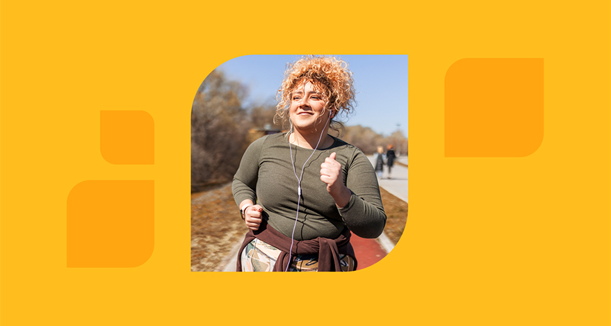 A person with long hair runs outdoors while wearing earbuds.